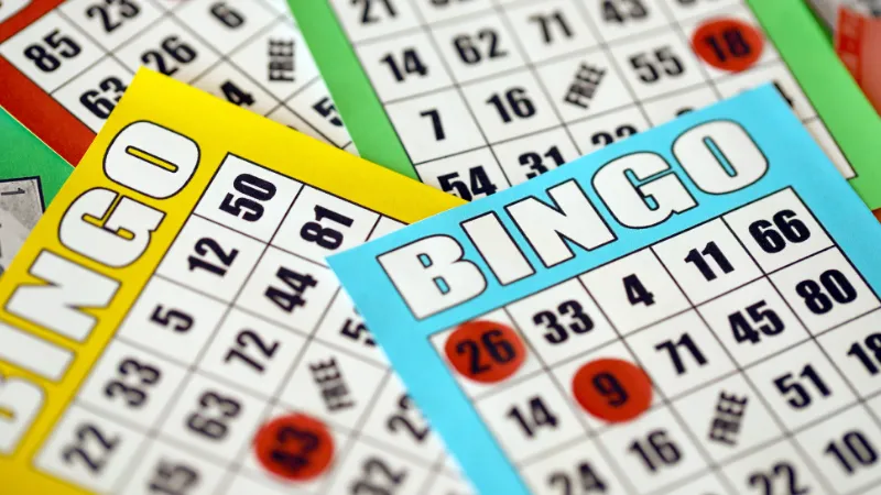 Colourful bingo cards in yellow, blue and green overlapping each other, with red counters marking called numbers.