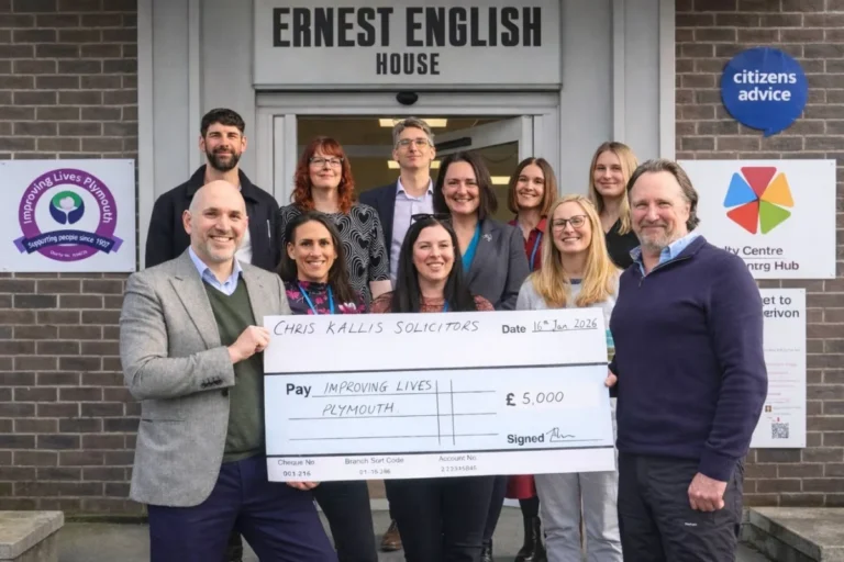 Group of people from Chris Kallis Solicitors presenting a large ceremonial cheque for £5,000 to Improving Lives Plymouth outside Ernest English House, dated 16th January 2026, with Citizens Advice signage visible in the background.