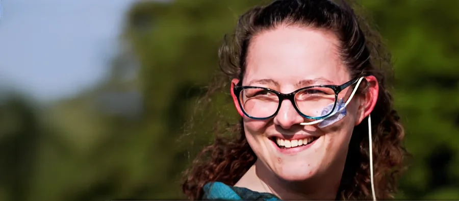 A woman smiling outdoors in soft afternoon light.